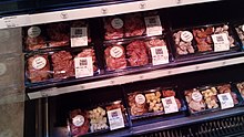 Numerous meats packaged in freezer of a supermarket