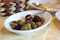 Il versamento d'olio d'oliva fresco; così come si usa fare anche in Sicilia. Olive provenienti da Castelvetrano, nel trapanese. Olive condite servite in un agriturismo siciliano.