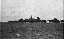 Large multiple rock outcroppings located in the middle of the ocean with a lighthouse located in the center as seen through a submarine periscope.