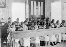 Indigenous children working at long desks