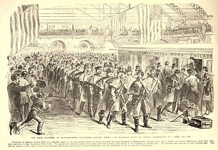 A black and white lithograph depicting a long column of soldiers at a large train station preparing to board a train