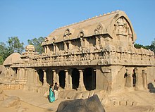 Внешний вид большого каменного храма, рядом с которым изображены мужчина и женщина.