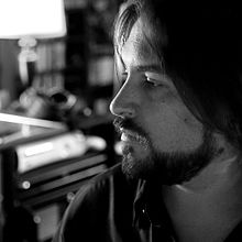 Neil Acree in his studio. This is a profile shot with Acree looking left with composing equipment in the background