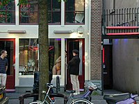 A sex worker in Amsterdam's red-light district talks with a potential client. Prostata Prostitute.jpg