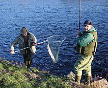 man and angler along river with salmon