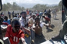 US Navy 100116-N-6006S-063 Haitian citizens receive water from U.S. Navy air crewmen from Helicopter Sea Combat Squadron (HSC) 9, assigned to the aircraft carrier USS Carl Vinson (CVN 70).jpg