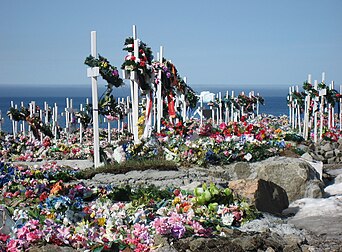 Le cimetière d'Upernavik, au Groenland. Le sol ne pouvant être creusé, les cercueils sont déposés en surface puis recouverts de pierres ou de ciment. Les tombes sont décorées avec des fleurs artificielles. (définition réelle 2 200 × 1 622)