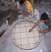 Artesanos trabajando en la elaboración de una mesa de mosaico.