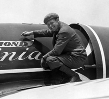 Photographie de George R. Hutchinson, accroupi sur l'aile de l'avion.