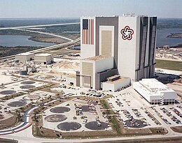 VAB in 1977, with the Bicentennial Star opposite the flag. The Bicentennial Star was painted over with the NASA insignia in 1998. Note the Space Shuttle Landing Facility at upper left. VAB aerial 1977.jpg