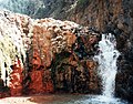 Durch Mineralien gefärbter Wasserfall in der Caldera