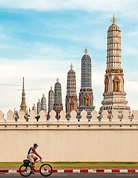 Cycliste devant les huit Chedis Phra Atsada Maha et la flèche du Koei Sadet, porte du temple du Bouddha d'émeraude, à Bangkok. (définition réelle 3 133 × 4 034)