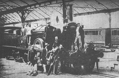 Impulsors, accionistes i enginers que feren possible el tren de Barcelona a Mataró davant la locomotora número 12 a l'estació terme de Barcelona (1848). Origen: El carril de Mataró al directo de Madrid de Antonio R Dalmau. Ed Llibreria Milà 1946