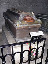 Photographie d'un sarcophage sur un socle en pierre, avec un médaillon le nom de l'empereur