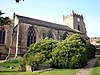 A stone church showing the nave with large three-light windows and a west tower.