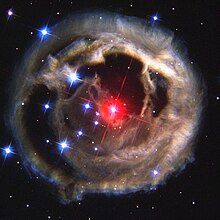 A red star lies at the centre of a brownish cloud against a background of stars