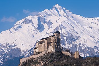 Castelo de Valère e a montanha Haut de Cry ao fundo. O castelo é uma igreja fortificada localizado em uma colina em Sião, no cantão do Valais, Suíça. Está voltado para o Castelo de Tourbillon, na colina oposta. O edifício principal do castelo é a basílica de Notre-Dame de Valère. Construído nos séculos XII e XIII foi a residência dos cânones do colégio de clérigos. Eles viveram lá até a Revolução Francesa. As antigas dependências dos cânones agora abrigam o Museu de História do Valais, fundado lá em 1883 e totalmente reformado em 2008. A basílica também pode ser visitada e é possível ouvir o órgão mais antigo do mundo (1430) durante um festival anual: o Festival Internacional do órgão antigo e da música antiga. Valère obteve o título de basílica menor durante a visita do Papa João Paulo II em 1984. (definição 4 967 × 3 311)