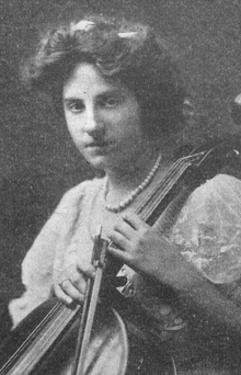 A young white woman holding a cello and bow.