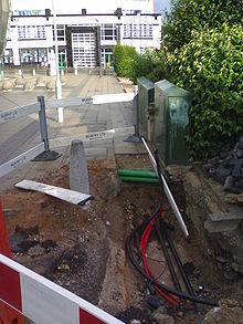 Exposed cables using for carrying cable TV. The green box is a common sight in areas with cable coverage, as are manhole covers inscribed with CATV. Virgin Media cables revealed under pavement.jpg