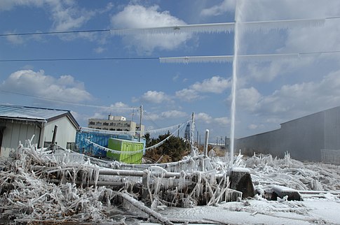 A damaged water pipe shoots into the air after the tsunami. слика: -{U.S. Navy}-.