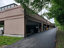 A paved trail next to a two-story parking garage