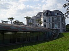 Photographie en couleurs d'un bâtiment ancien au milieu d'un parc.