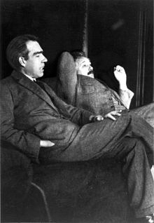 Hai nhà khoa học đang ngồi thư giãn. Bohr với mái tóc đen đang nói chuyện với Einstein.