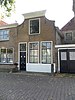 Huis met ingezwenkte lijstgevel met stoep en stoeppaal