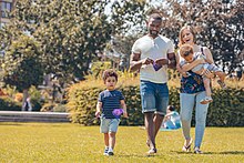 A mixed-race family walking in a park with European flags (P044728-798775).jpg