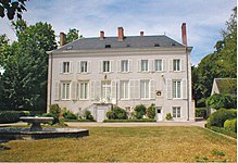 Photographie en couleurs d'un château de deux étages, le toit étant en ardoises ; une pelouse au premier plan.