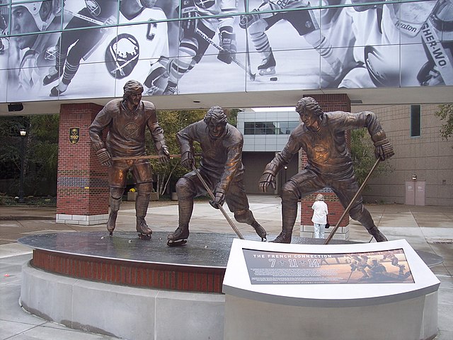 A bronze statue of the three players outside of an arena