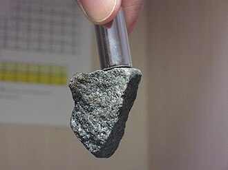 A magnetite rock is being pulled by a neodymium magnet on top. Magnetite sample with neodymium magnet.jpg