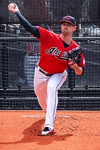 A man in white baseball pants, red jersey, and navy under-sleeves and cap