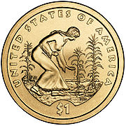 Pièce de monnaie représentant une femme plantant des graines dans un champ peuplé de maïs, de haricots et de courges. En plus les inscriptions UNITED STATES OF AMERICA, NEN et $1.