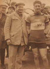 Photographie d'un coureur cycliste en tenue posant à côté d'un homme en costume.