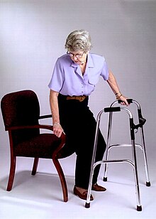 Photographie d’une personne âgée s’asseyant sur un fauteuil rouge.
