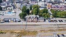 Drohnenfoto von einem Bahnhofsgebäude, dahinter städtische Bebauung