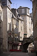 Photographie en couleurs en couleurs d'une petite rue sur laquelle passe l'arche en pierre d'un pont.