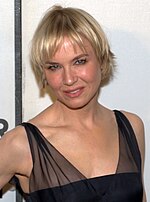 Profile of a female with short blonde hair wearing a black dress.