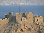 Medieval castle with a flag of Egypt, sea in the background
