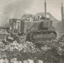 Photo noir et blanc d'un bulldozer roulant sur des ruines.
