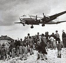 Berliners watching a transport bringing food and coal during the Berlin Blockade of 1948-1949 C-54landingattemplehof.jpg