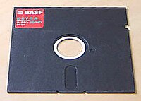 A 5-inch disk with a partly exposed magnetic medium spun about a central hub. The cover has a cloth liner to brush dust from the medium. Note the "write-enable slot" to the upper right and the strobe hole next to the hub that regulates drive speed.