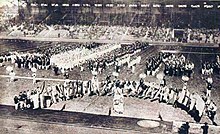 Black and white image of national teams marching into the stadium behind their national flag