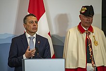 Federal Councillor Ignazio Cassis speaks in 2019 accompanied by a Bundesweibel Secretary Pompeo Holds Press Availability with Swiss Foreign Minister Cassis (47991315853).jpg