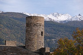 Rounded tower in front of a mountainous landscape.