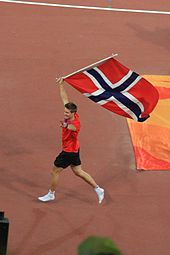 Photographie de Andreas Thorkildsen brandissant le drapeau norvégien