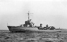 Photographie en noir et blanc d'un navire de guerre en mer, la proue pointant vers la gauche de l'image.