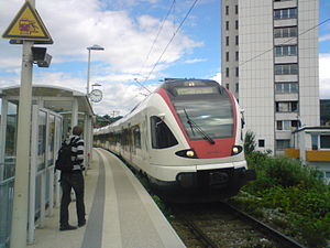 White-and-red train arrives at side platform