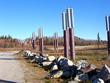 Most road crossings are simply buried deep, but this crossing on the Richardson Highway is close to the surface and employs thermosyphons, special heat pipes that conduct heat from the oil to the fins at the top of the pipes in order to avoid thawing the permafrost Heatpipes.JPG
